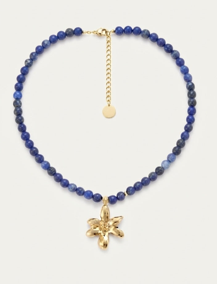 Collar lapislázuli bolas azules con colgante flor dorada sobre fondo blanco, vista completa