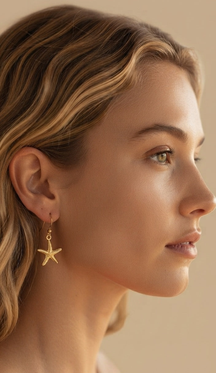 Pendiente estrella de mar dorado puesto en modelo de perfil