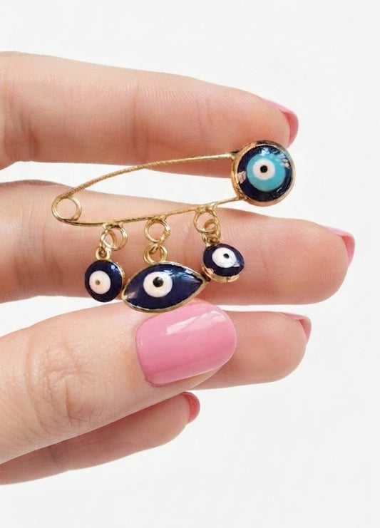 Broche imperdible ojo turco dorado sostenido en mano - detalle colgantes