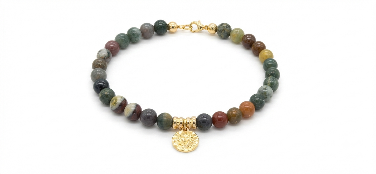 Pulsera de ágata india con moneda dorada sobre fondo blanco