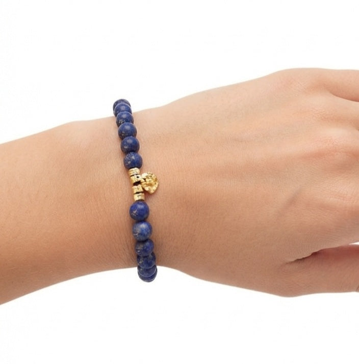 Pulsera de lapislázuli con monedita dorada sobre fondo blanco