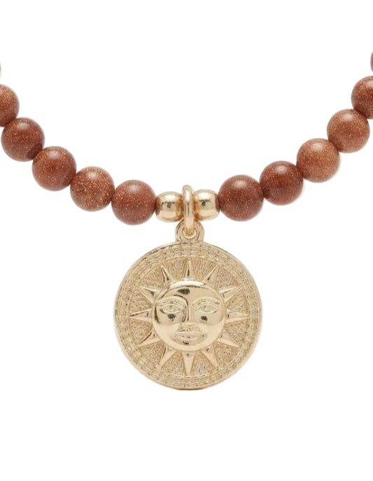 Detalle collar jasper rojo con medalla sol dorada