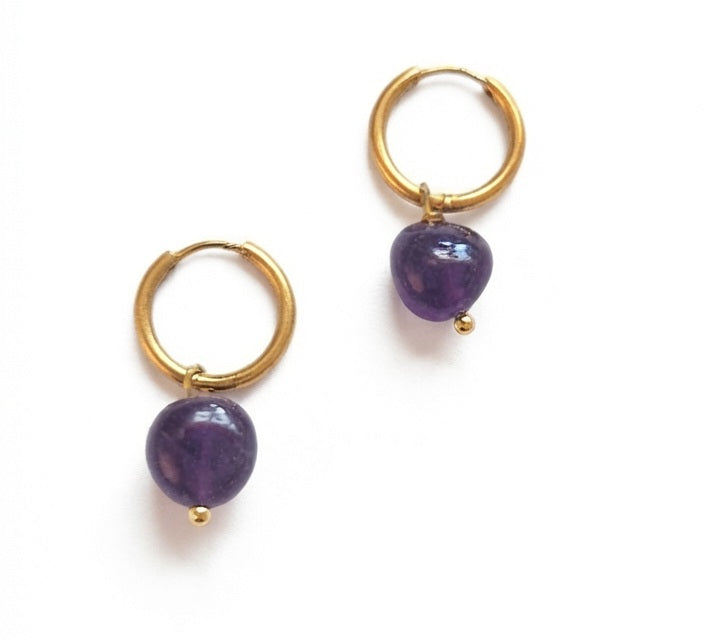 Par de aros de acero dorado con amatista natural sobre fondo blanco