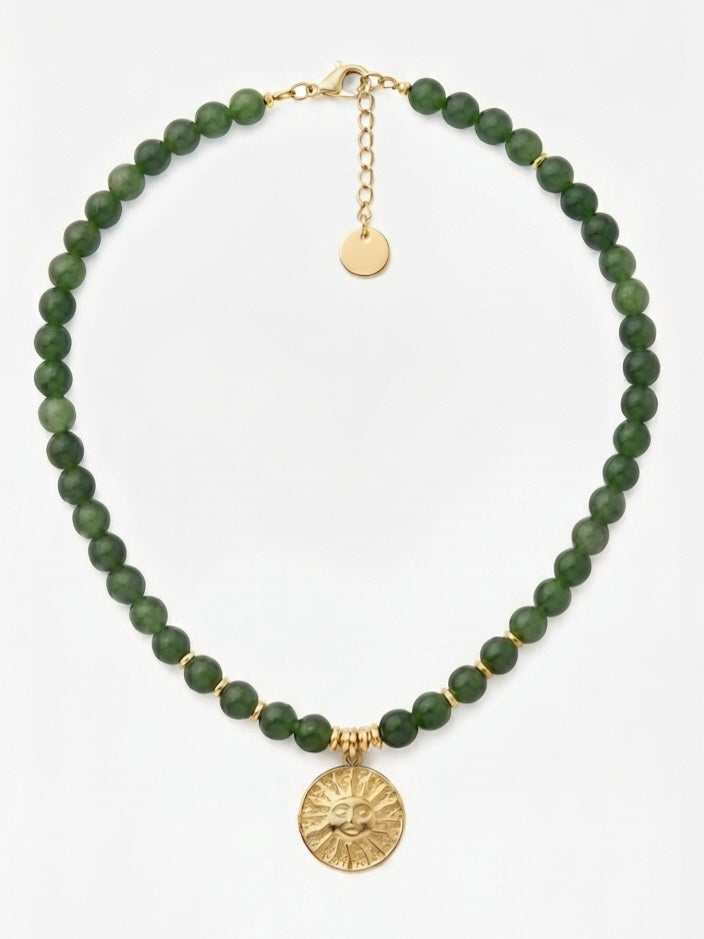 Collar jade verde con colgante sol dorado sobre fondo claro