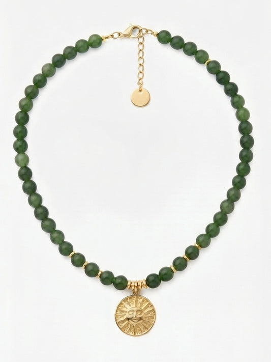 Collar jade verde con colgante sol dorado sobre fondo claro