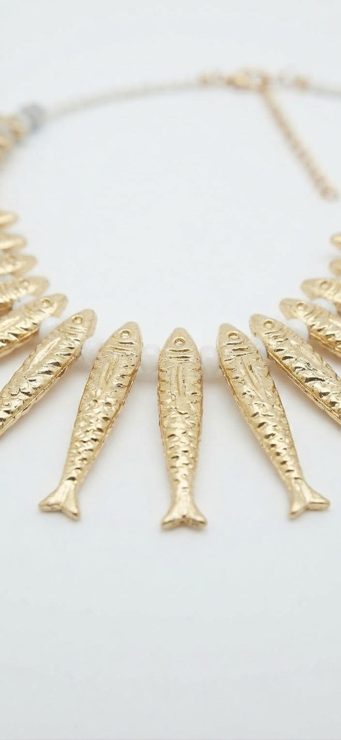 Detalle collar peces dorados sobre fondo blanco