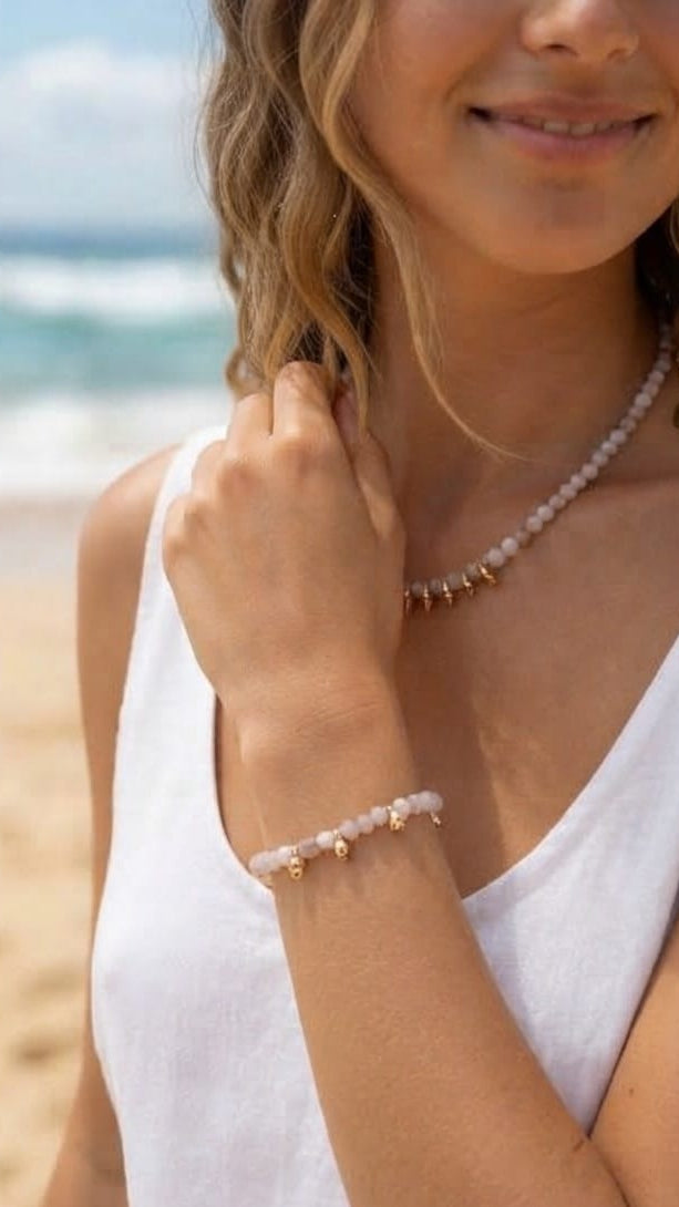 Modelo luciendo pulsera de ópalo rosa con pepitas doradas en la playa