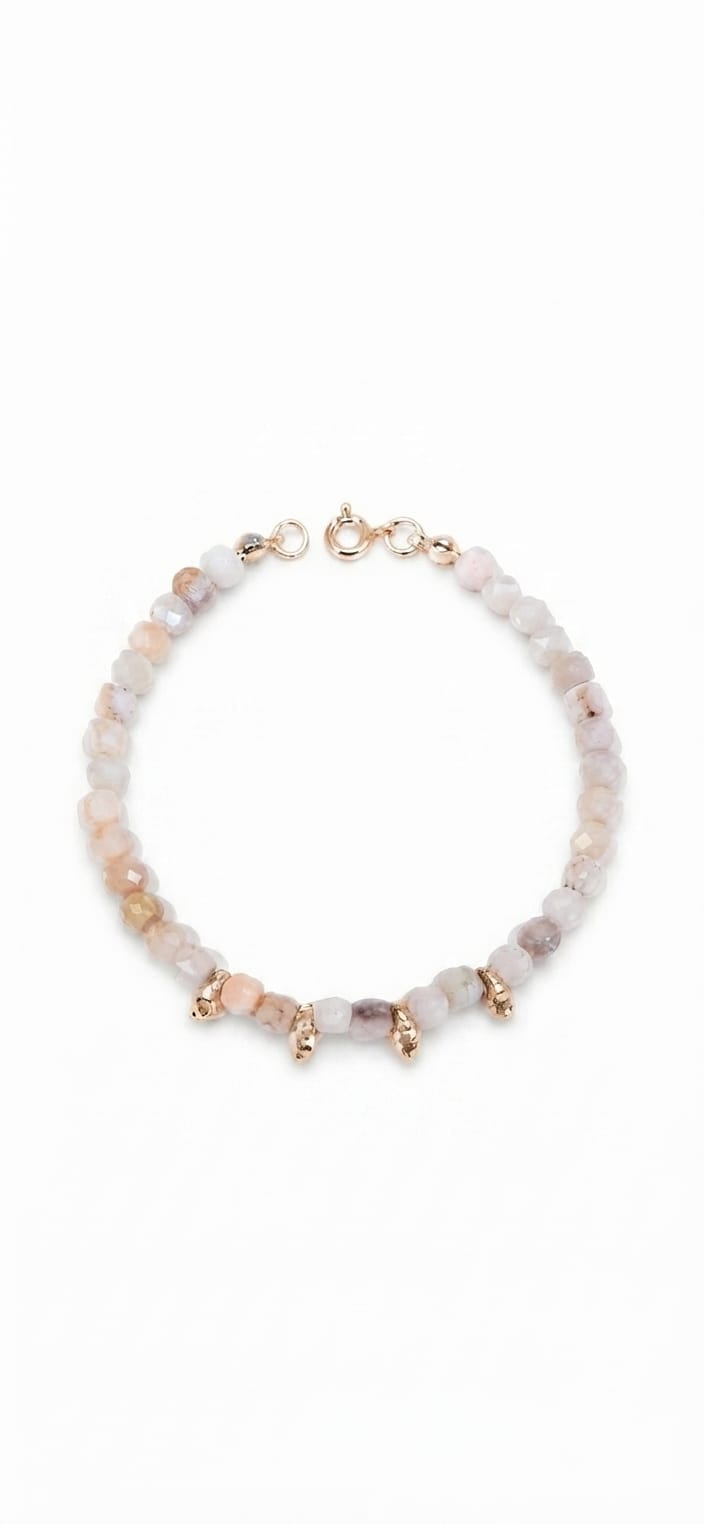 Pulsera de ópalo rosa con pepitas doradas sobre fondo blanco