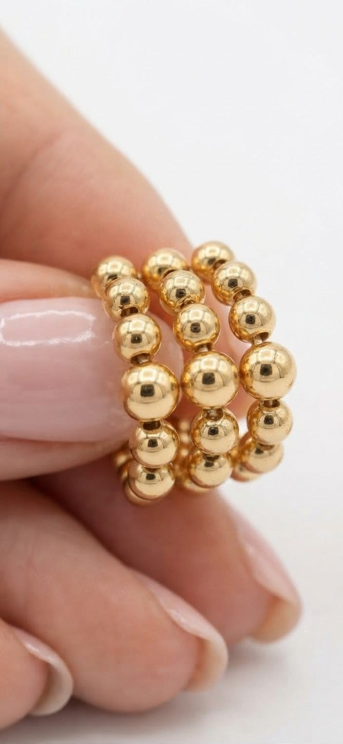 Aros bolas acero dorado en mano detalle