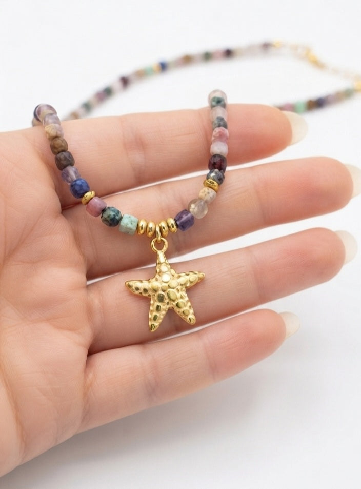 Detalle collar piedras semipreciosas con estrella de mar dorada en mano