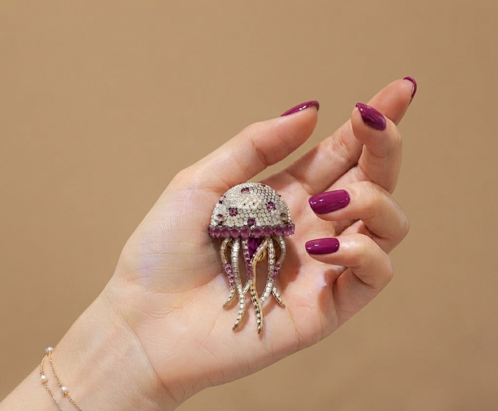 Broche medusa rosa dorado sostenido en mano - escala real