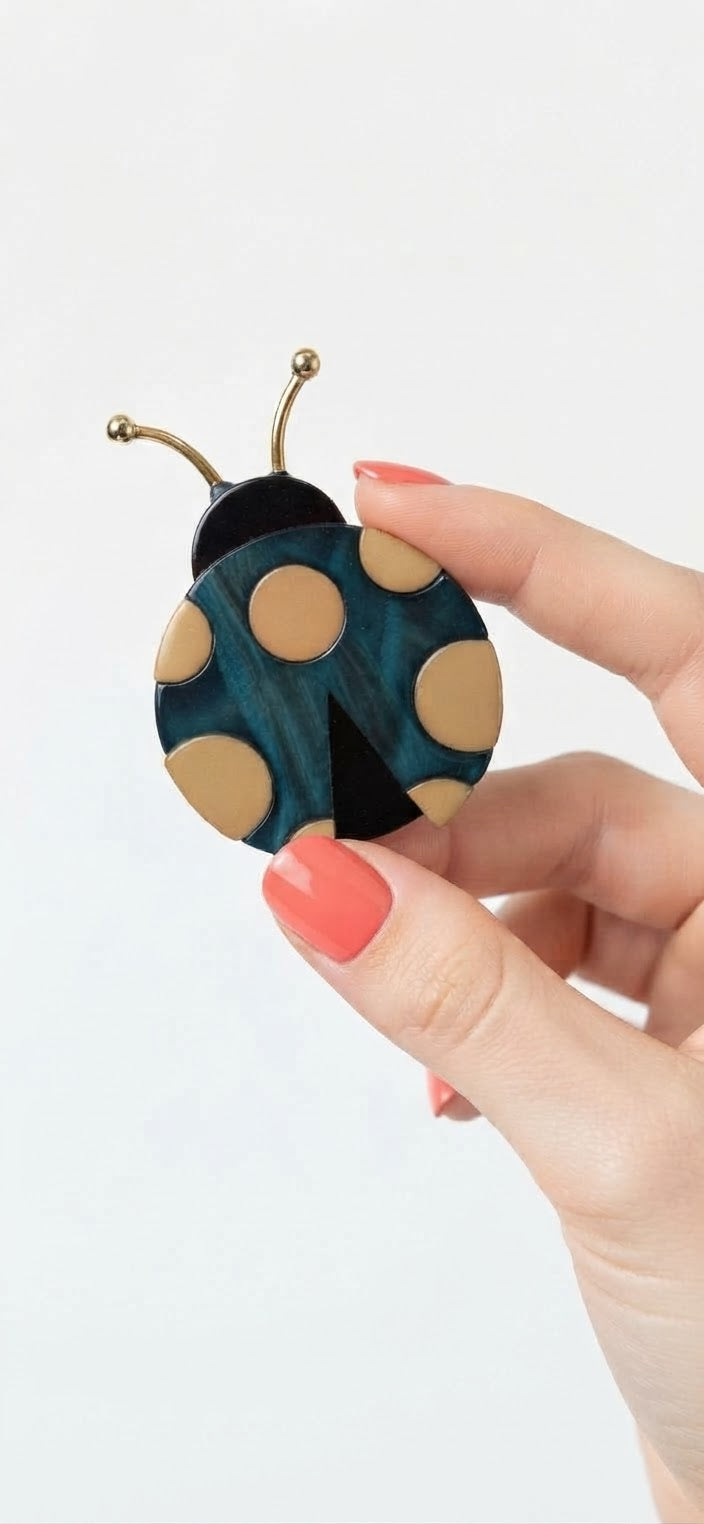 Broche mariquita acrílico azul cián - escala en mano