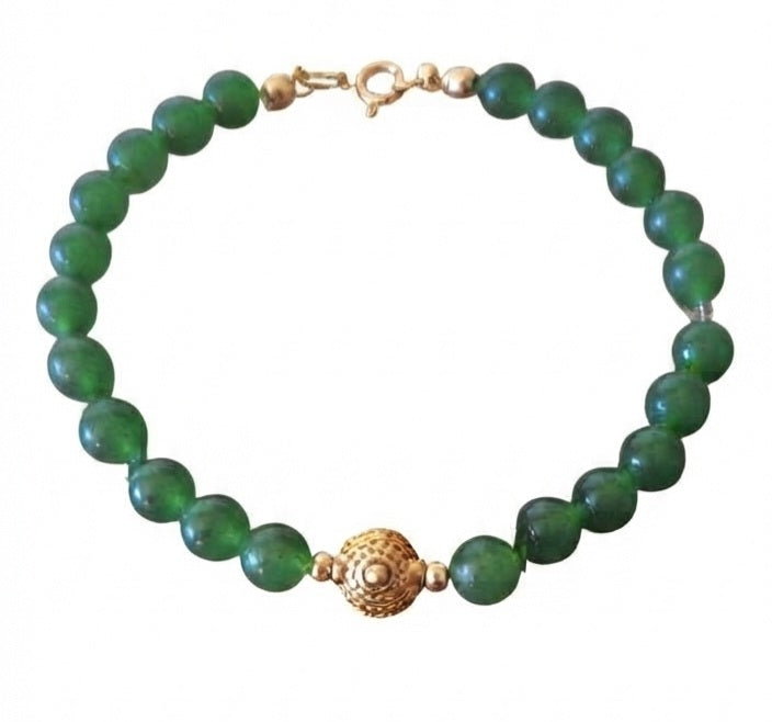 Pulsera jade verde con entrepieza filigrana dorada sobre fondo blanco